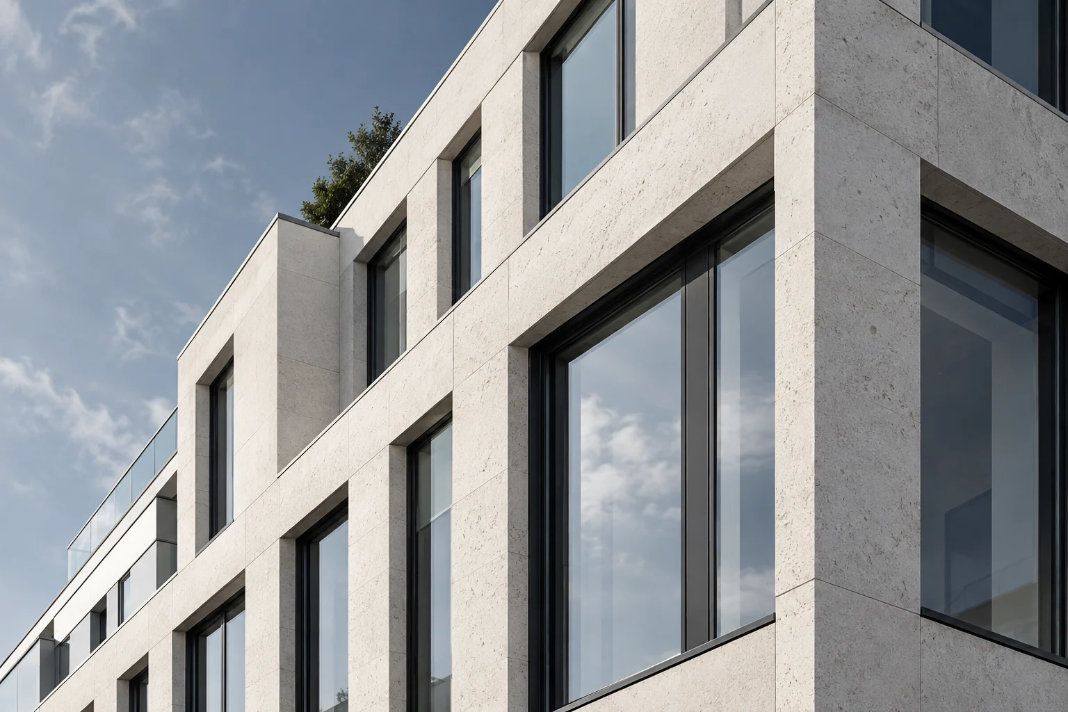 Klare Linien einer hellen Steinfassade mit dunklen Fensterrahmen